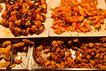 Variety of meat and seafood products are prepared and displayed on trays for visitors