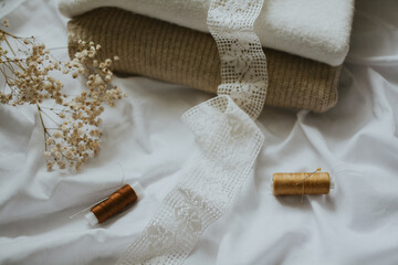 white patterned fabric ribbon and brown threads with needles against a background of delicate colors