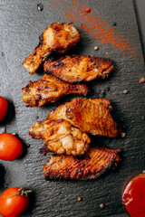 Juicy grilled chicken wings served with fresh tomatoes and spices, perfect for a delicious meal