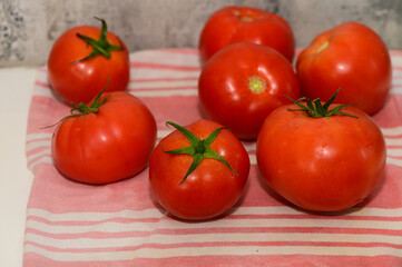 Freshly picked ripe tomatoes arranged on a striped cloth in a simple kitchen setting