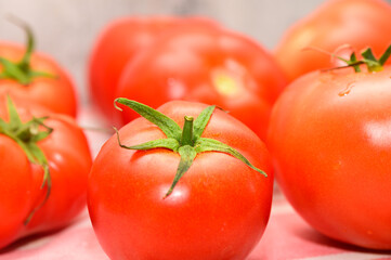 Vibrant red tomatoes arranged artistically on a textured surface, showcasing fresh produce in...