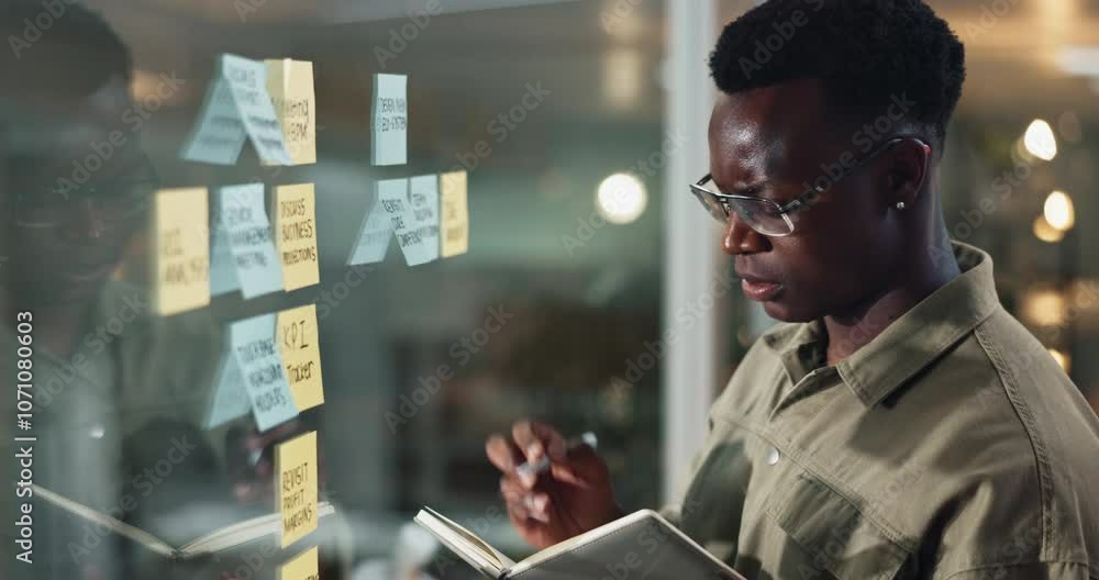 Poster notebook, glass wall and black man in office at night with research for planning, brainstorming or p