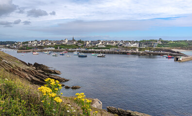 A scenic view of a coastal town of Conquet, Brittany, with numerous boats anchored in a calm bay,...