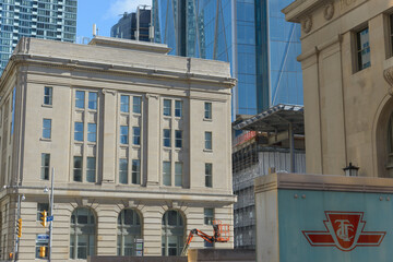 Fototapeta premium looking southeast on Front St W to old building, public transit logo, and office towers at CIBC Square in Toronto, Canada