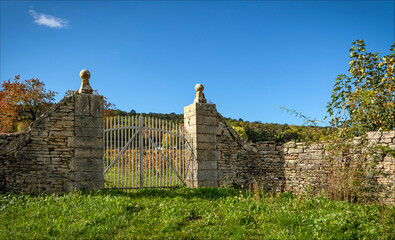 Stone gateway with white painted gate leading into a vineyard