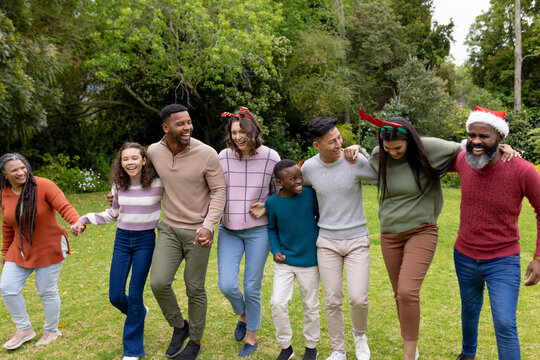 Diverse multiracial family celebrating Christmas outdoors, walking together and smiling joyfully