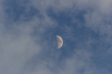 Moon in the blue sky with white clouds, closeup of photo