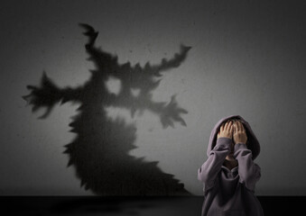 Little kid scared by monster. Spooky shadow on grey wall