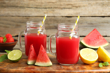 Tasty watermelon drink in mason jars and fresh fruits on wooden table