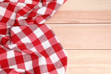 Obraz premium Crumpled tablecloth with checkered pattern on light wooden table, space for text