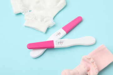 Pregnancy tests and socks on light blue background