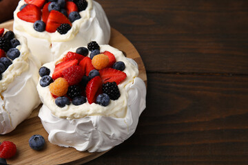 Pavlova cake (meringue dessert) with whipped cream and fresh berries on wooden table, closeup....