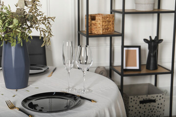 Stylish table setting with black dishware in dining room