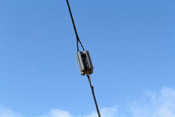 Obraz premium Insulator attached to a power electricity line cable with a blue sky background