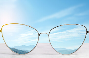 Glasses against beautiful landscape. View through lenses more clear. Vision correction