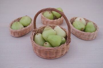 Ripe green wax apple in a basket on a wooden background.