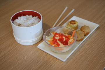 Japanese food in white bowl with chopsticks on wooden table background.