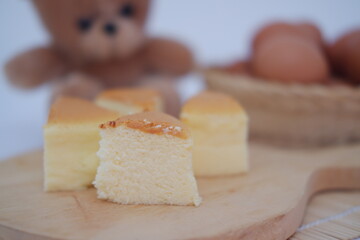 Cheesecake on cutting board and eggs in background.