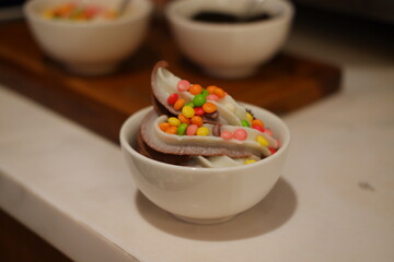 Chocolate ice cream with colorful candies on the white background.