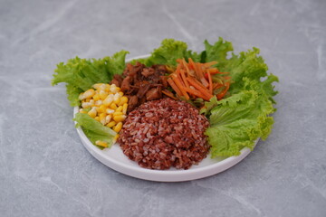 Red rice with fried egg and vegetables on white background.
