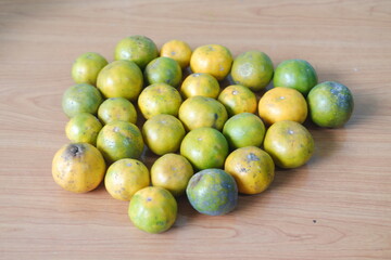 A bunch of fresh oranges displayed on a wooden table
