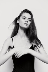 Fototapeta premium Elegant young woman with long hair in black top, posing with natural beauty and confidence. Black and white portrait emphasizing grace and poise.