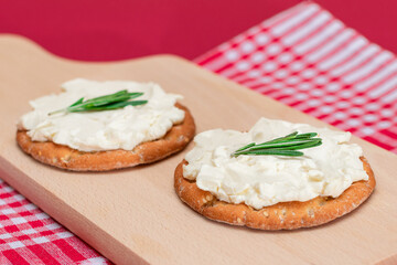 Crispy Cracker Sandwich with Cream Cheese and Rosemary on Wooden Cooking Board on Magenta Background