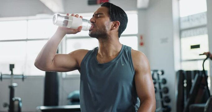 Man, fitness and drinking water in gym for tired, exercise and break with challenge, cardio and workout. Body builder, hydration liquid and breathing in sports club for fatigue, recovery and health