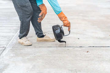 Workers pour hot asphalt on the joint cement concrete floor.