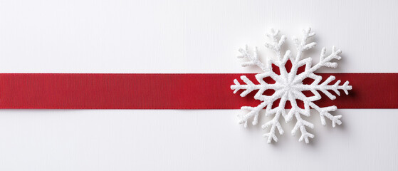 A white snowflake decorates a red ribbon against a plain background, evoking a festive winter or holiday theme.