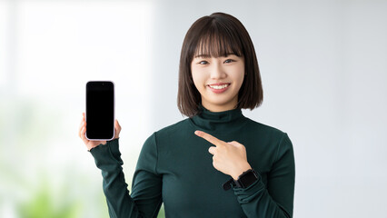 スマホを指差す笑顔の若い女性・ビジネスウーマン
