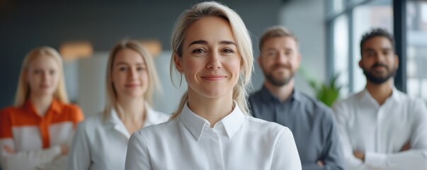 Fototapeta premium A confident woman smiles in front of a diverse group of colleagues, showcasing teamwork and professionalism in a modern office environment.