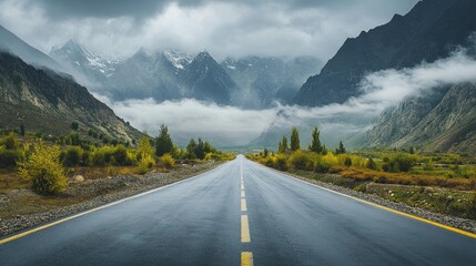 Fototapeta premium Serene Mountain Road Under Clouds and Fog
