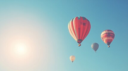 Obraz premium Four colorful hot air balloons fly in a bright blue sky with a glowing sun in the corner.