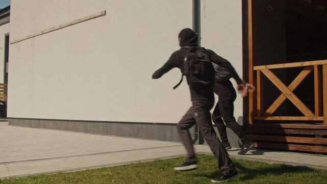 Two Armed, Masked Burglars Attempt a Break-In but Are Chased Away by a Guard Dog Protecting the Home. Concept of Home Security Pet Protection, and the Role of Guard Dogs in Deterring Criminal Activity