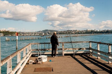 Fisherman at the End of Pier: Tranquil Seaside Fishing Scene