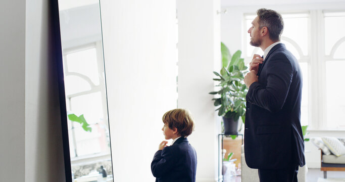 Father, child and help with tie for suit by mirror for event preparation, learning fashion or ready in family home. Dad, kid and boy in formal necktie, clothes and dressing with reflection of parent