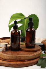 Amber Glass Pump and Dropper Bottles on Wooden Spa Setup with Green Leaves