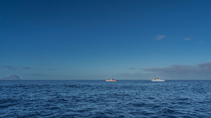 Tourist motorboats in the endless blue ocean. Ripples on the surface of the water. A mountain in...