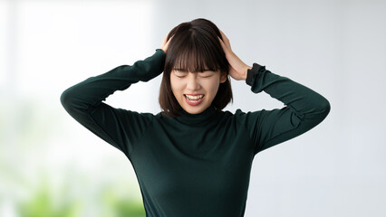 頭を抱えて困る若い女性・ビジネスウーマン