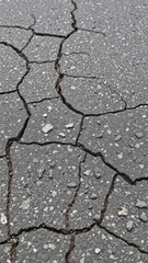 Obraz premium A close-up photo of weathered asphalt road surface with cracks and texture, construction, urban