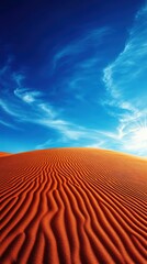 Naklejka premium A breathtaking view of undulating orange sand dunes beneath a vast blue sky, creating a serene and captivating natural landscape that invites tranquility and reflection.