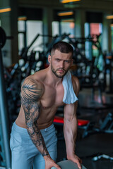 Fototapeta premium Motivated male athlete does exercise, bodybuilding workout at gym. Strong muscular man has fitness workout. Sport and healthy lifestyle concept. Muscular man workout in gym doing exercises with