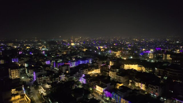 aerial drone shot rising over a group of lit densely populated houses with multicolor lights showing the celebration of the festival of lights diwali, new year, christmas