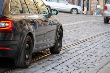 a passenger car is driving on a pavement with tram tracks in it