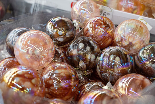 Colorful decorative Christmas ornaments in a box filled with pink shades.