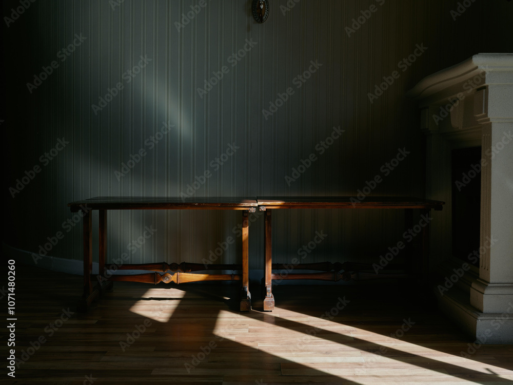 Wall mural Minimalist wooden table in a dimly lit room, with shadows creating a serene atmosphere Ideal for interior design and home decor concepts