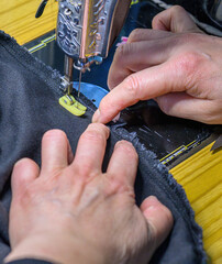 Hands of a woman operating a sewing machine.