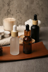 Elegant Aromatherapy Dropper Bottles with Natural Decorations and Candles on Wooden Tray