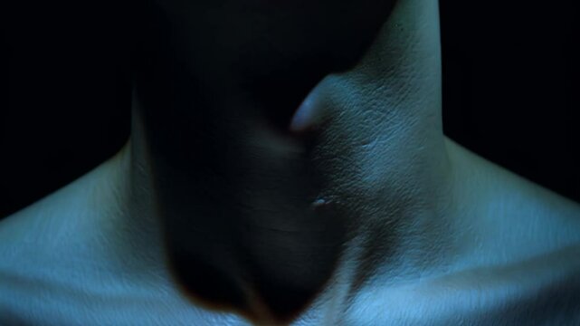 Close-up static video with low-key lighting, showcasing a neck and prominent adam's apple. the silhouette subtly moves.